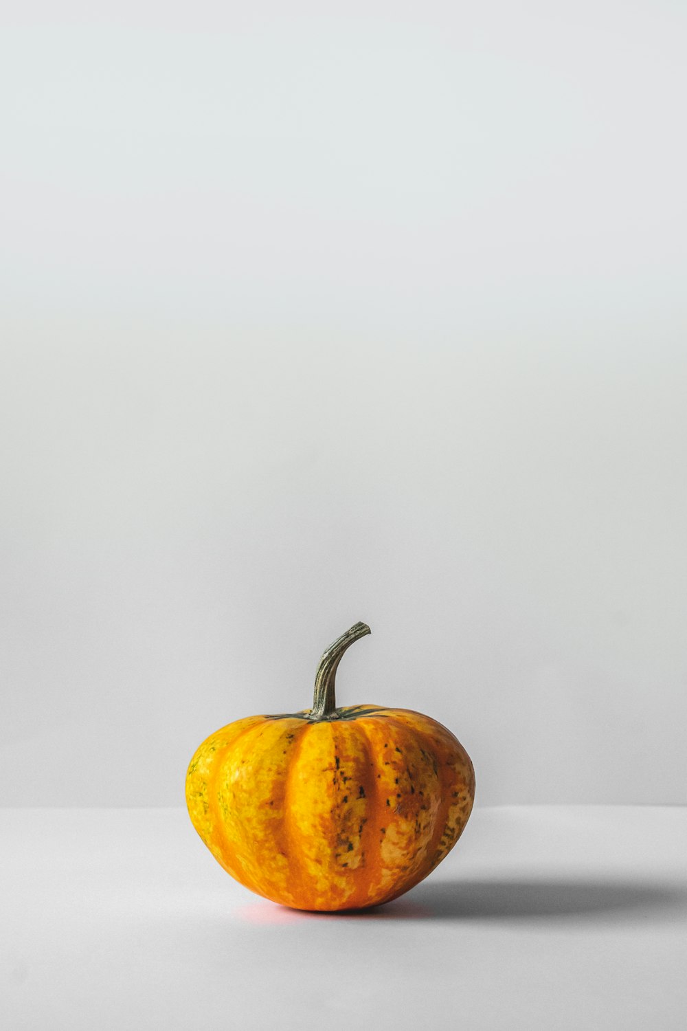 una zucca gialla seduta sopra un tavolo bianco