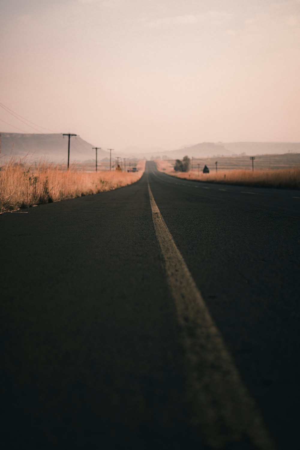 black asphalt road between brown grass field during daytime