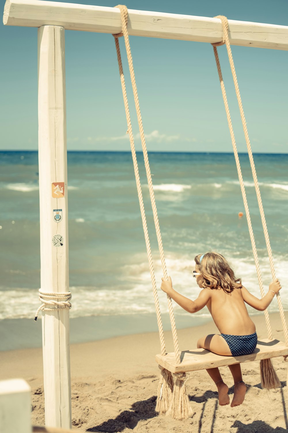 woman in black bikini sitting on swing during daytime