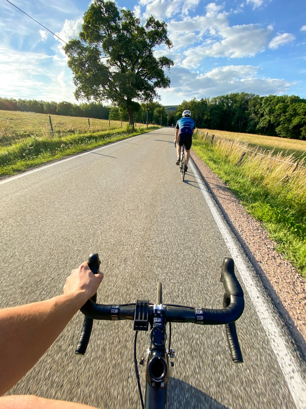 man in black t-shirt and blue denim jeans riding bicycle on road during daytime