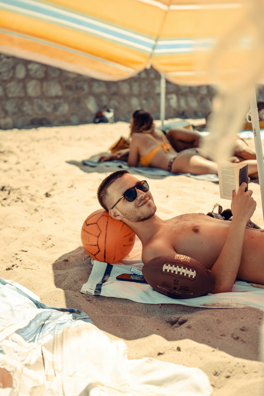 uomo in topless sdraiato su asciugamano bianco e blu sulla spiaggia durante il giorno