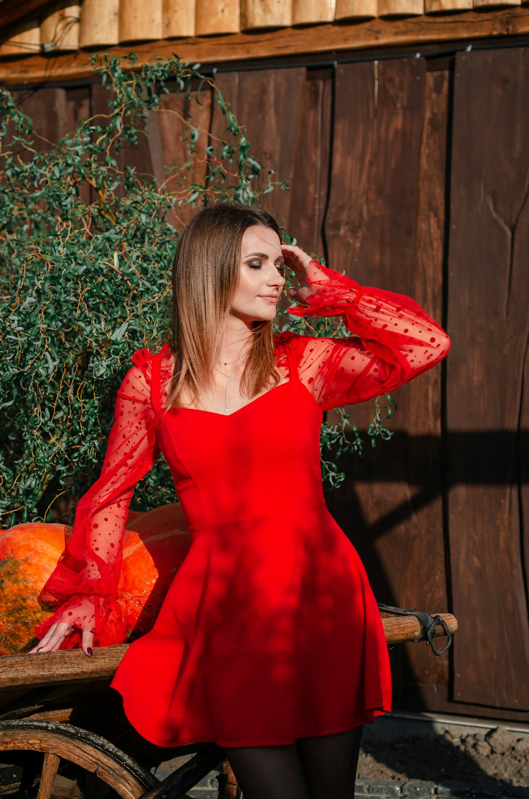 woman in red long sleeve dress sitting on brown wooden chair
