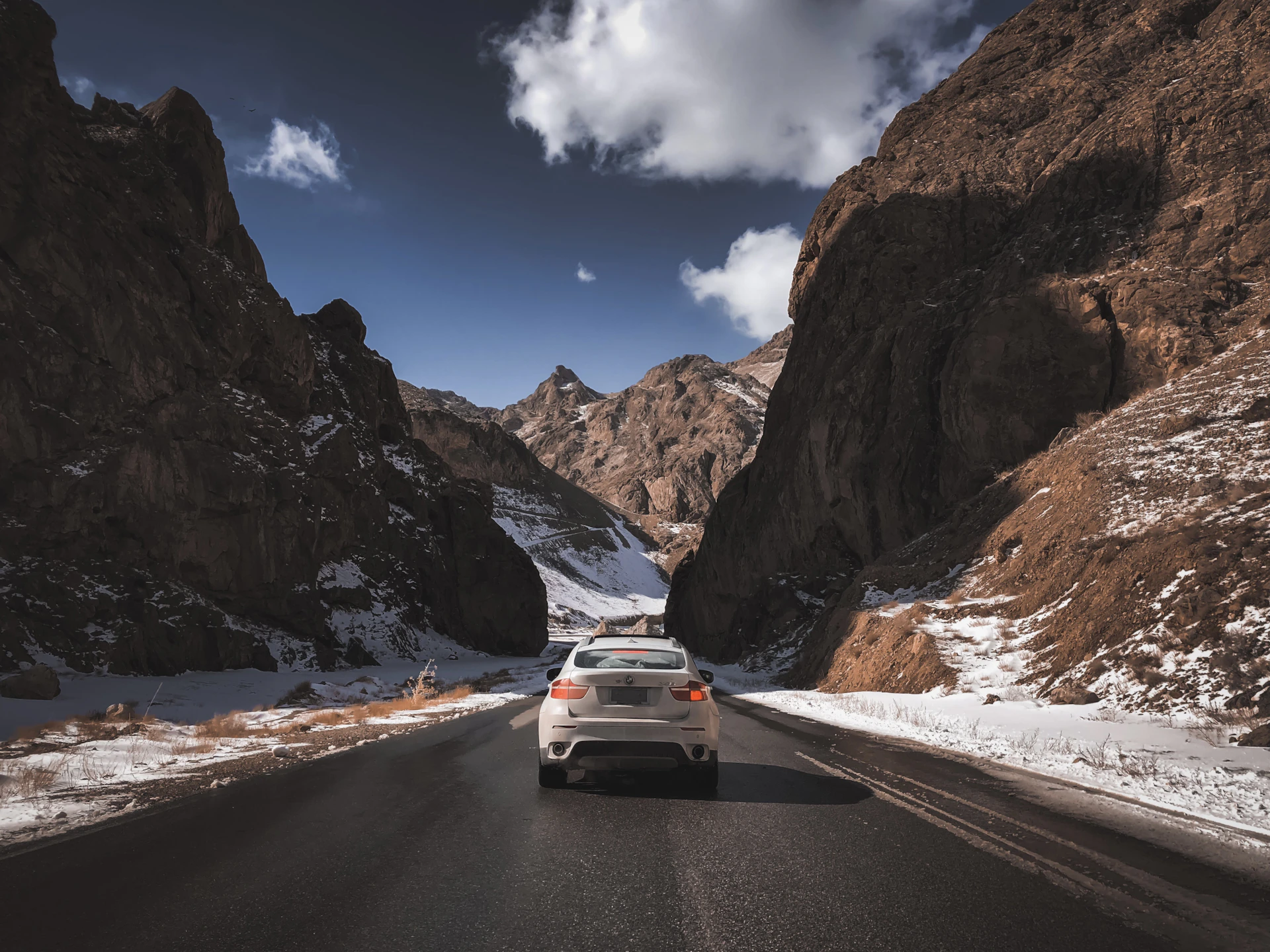 white car on road near brown rocky mountain under blue sky during daytime