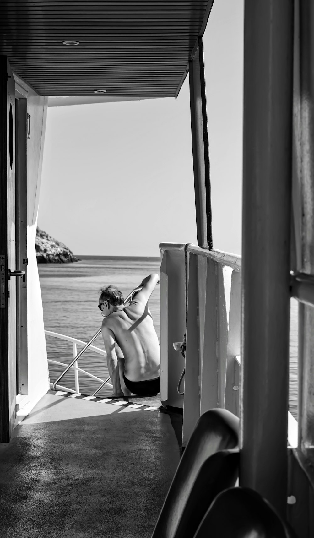 grayscale photo of woman sitting on chair by the window