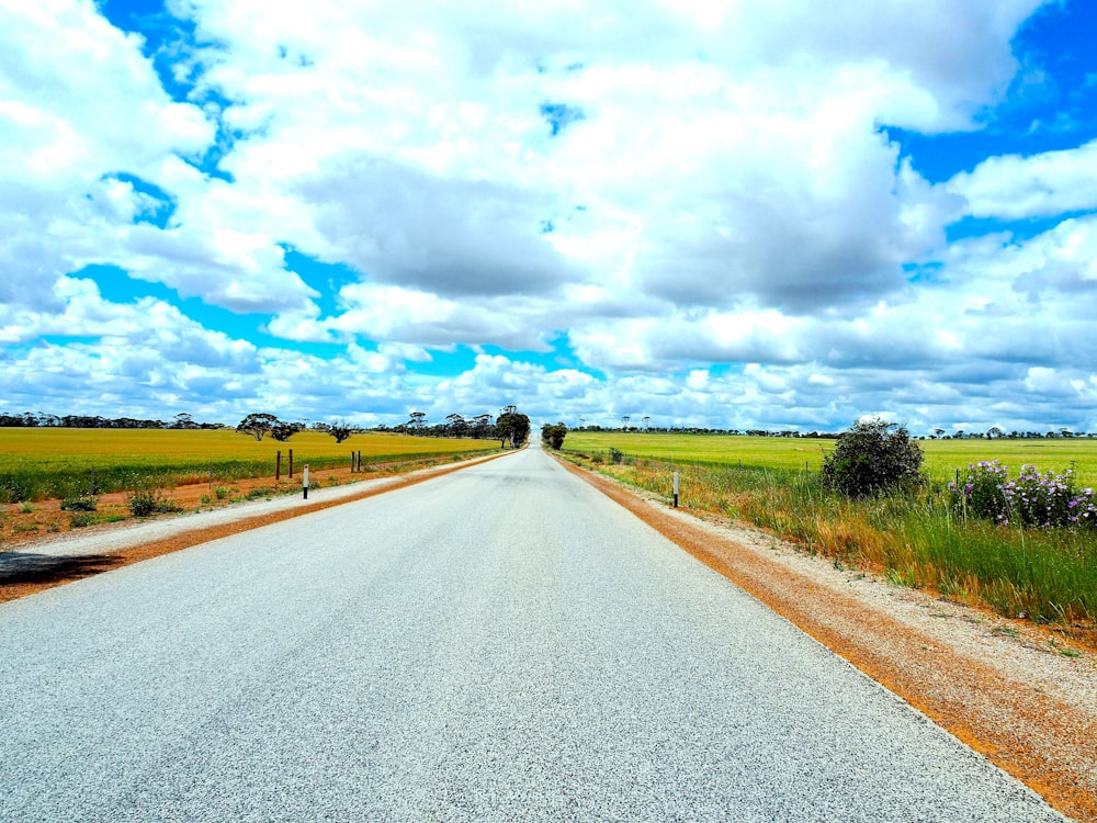 gray concrete road under white clouds and blue sky during daytime