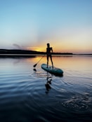 man in black shirt riding on green kayak on body of water during daytime