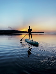man in black shirt riding on green kayak on body of water during daytime