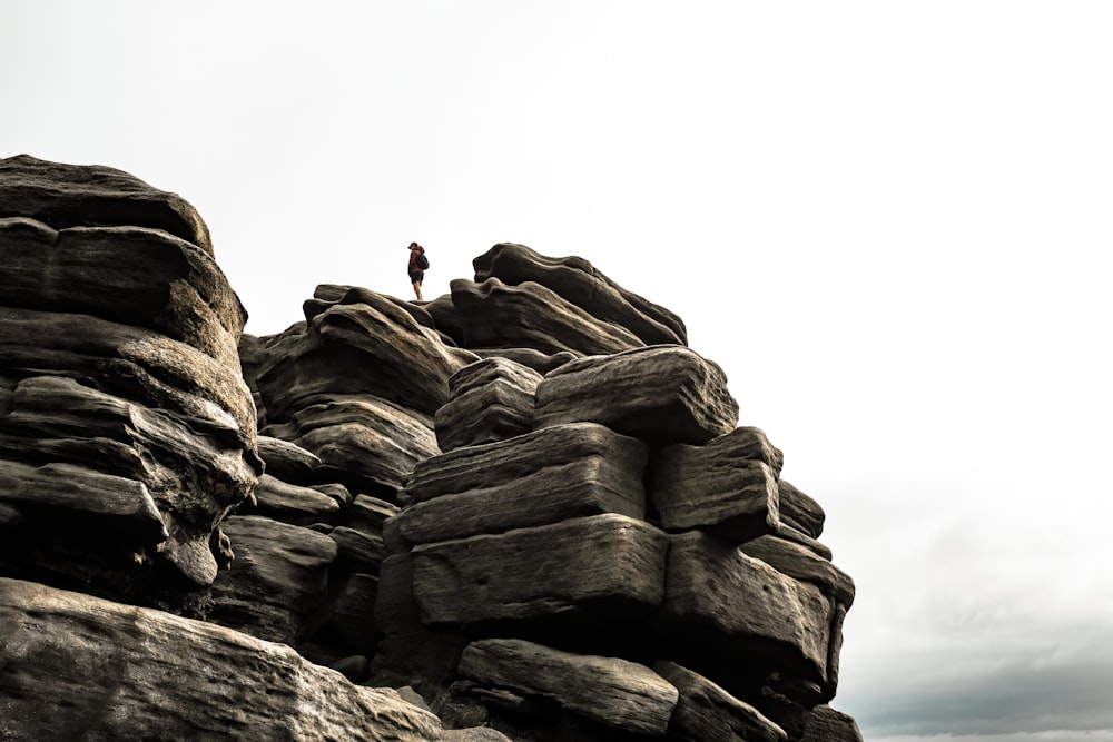 pessoa em jaqueta preta em pé na formação rochosa durante o dia