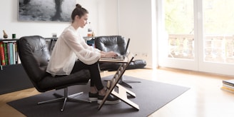 woman in white long sleeve shirt sitting on black leather armchair