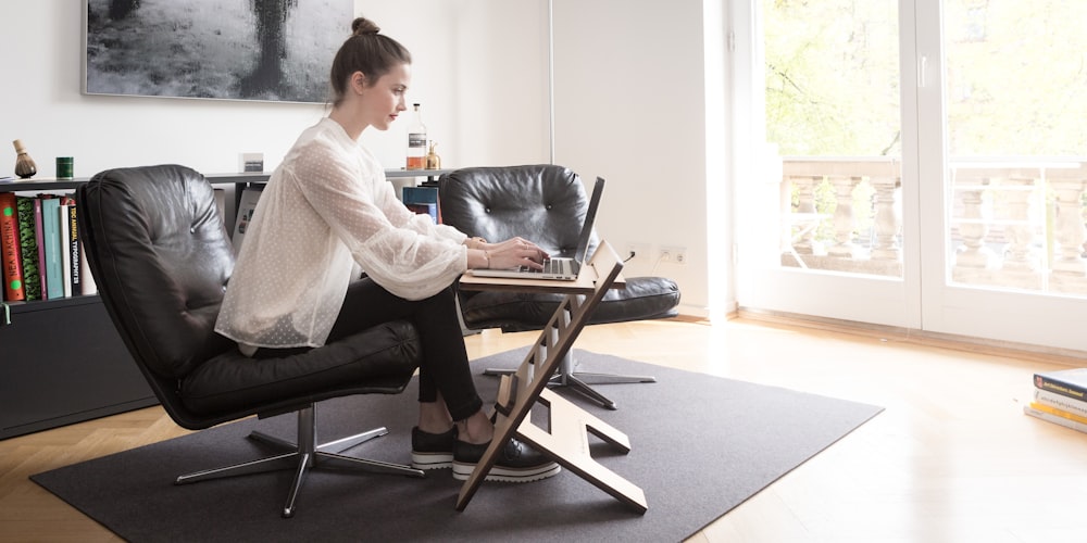 woman in white long sleeve shirt sitting on black leather armchair