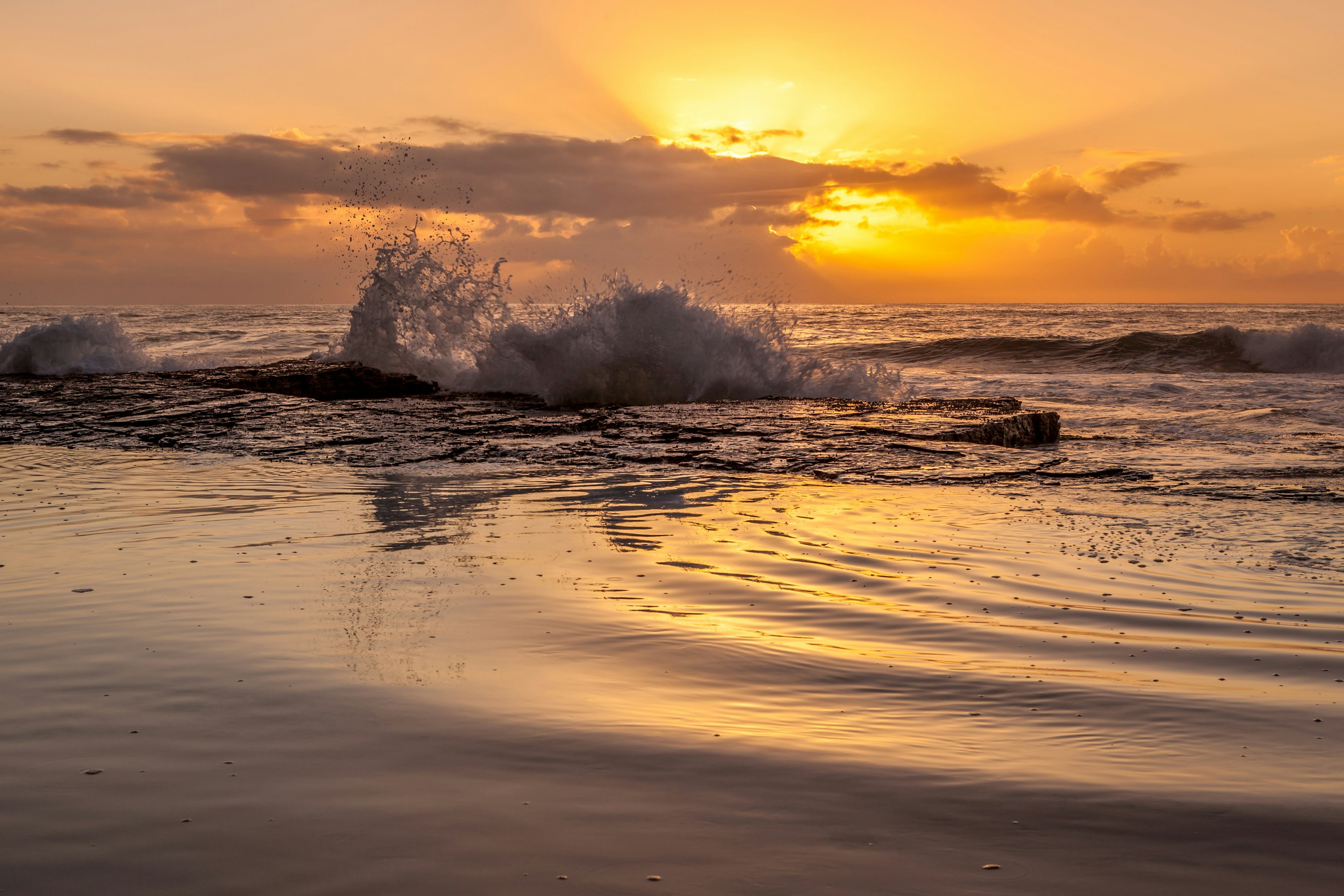 ocean waves crashing on shore during sunset