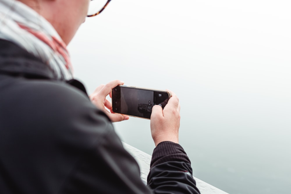 man in black jacket holding black smartphone