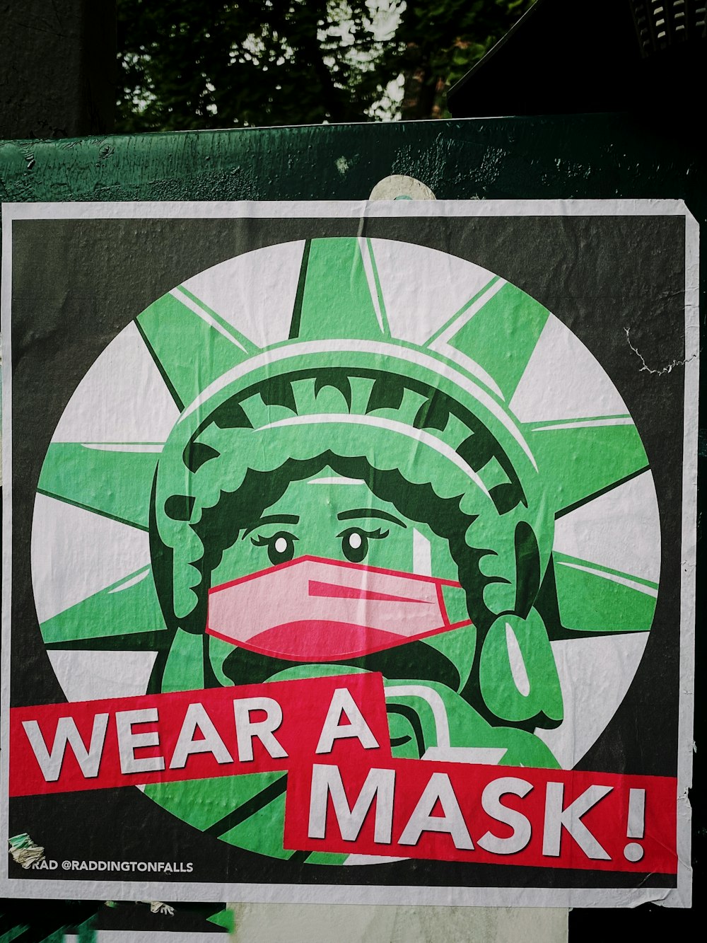 a sign that says wear a mask with a picture of the statue of liberty