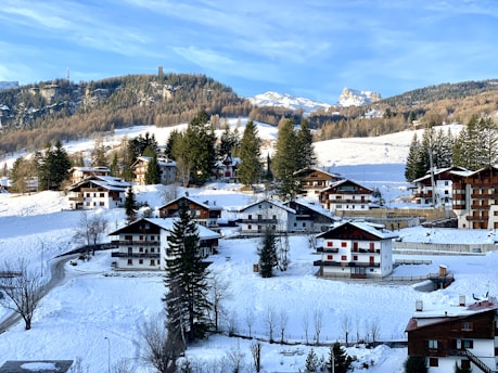 A charming Swiss chalet nestled in the mountains with snow-capped peaks in the background.