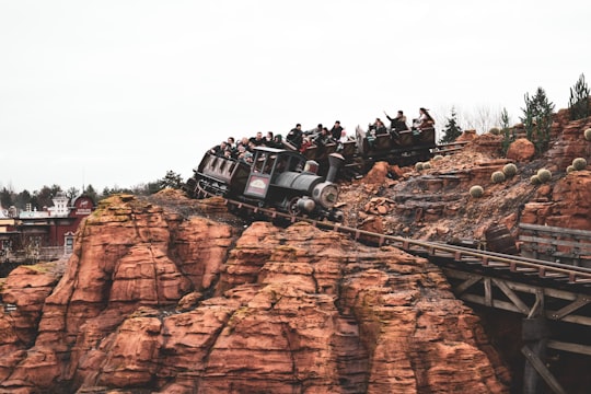 people riding on white suv on brown rocky mountain during daytime in Disneyland Paris France