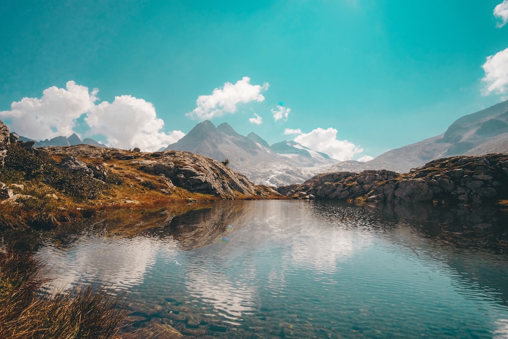 lake near mountain under blue sky during daytime