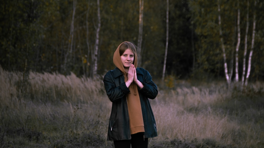 woman in black coat standing on forest during daytime