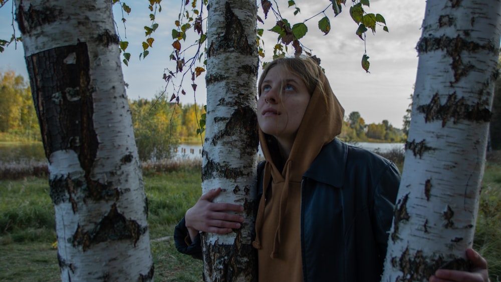 man in blue jacket standing beside tree