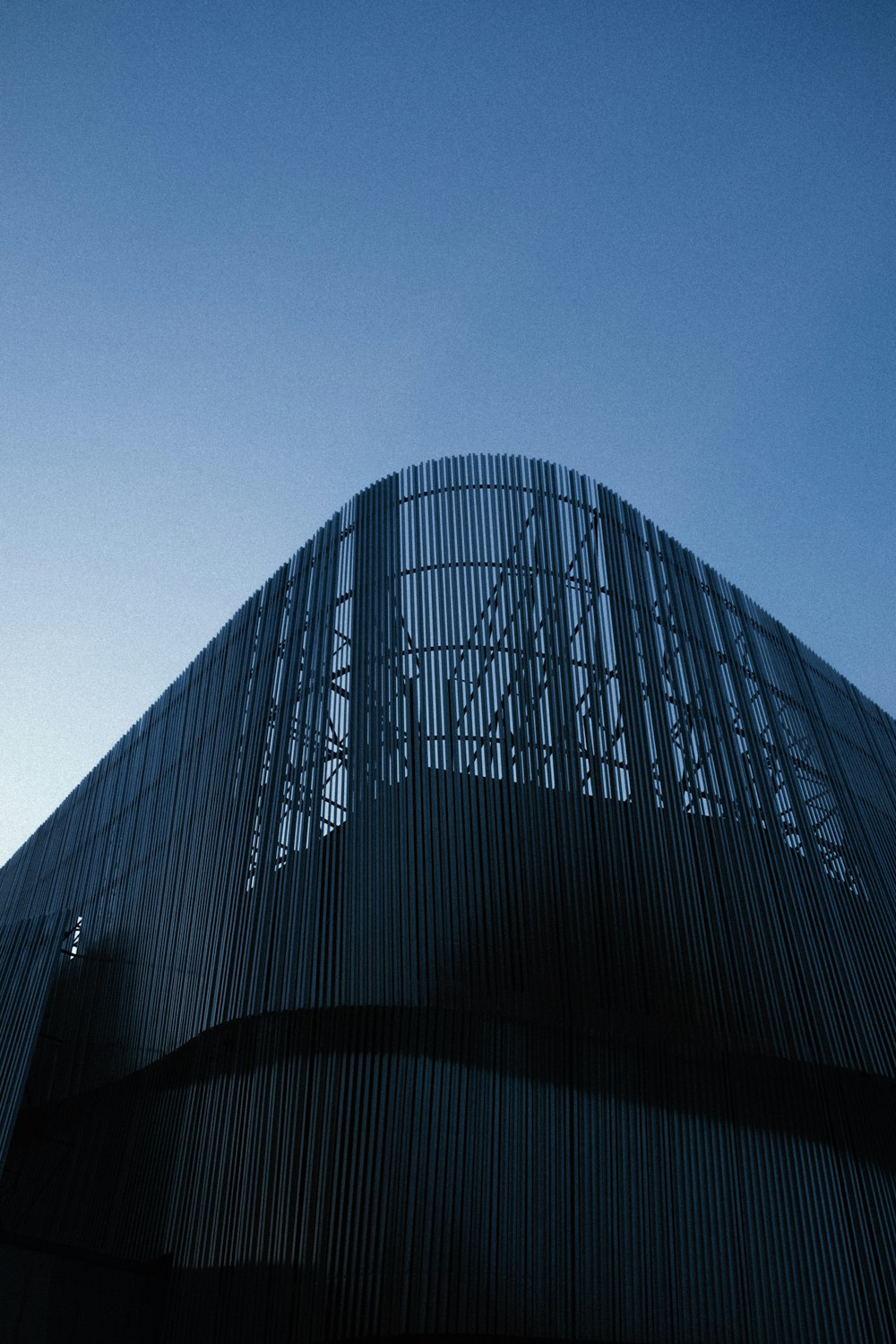 Edificio con paredes de vidrio negro bajo el cielo azul durante el día