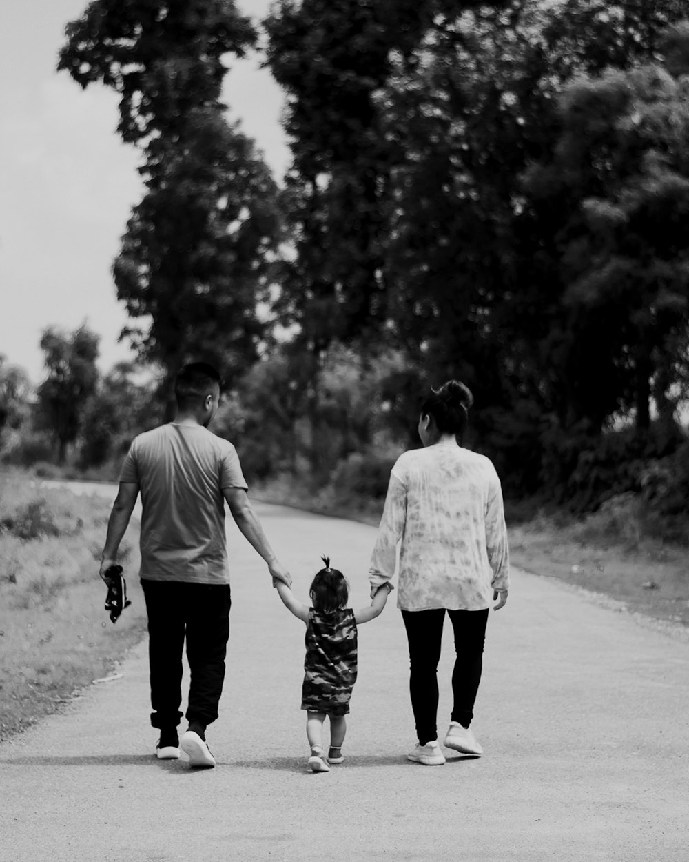 man and woman walking with dog on road