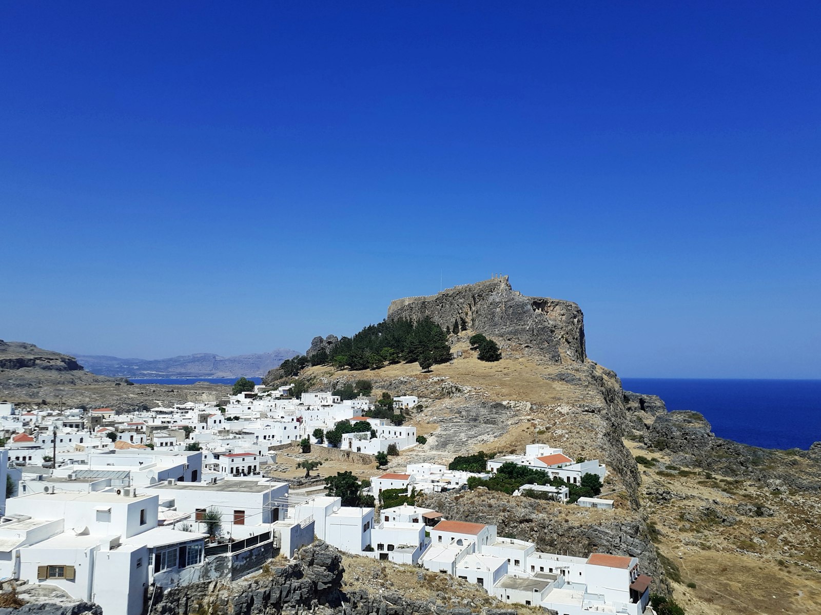 Whitewashed houses of Lindos on Rhodes below the rocky acropolis and its medieval walls
