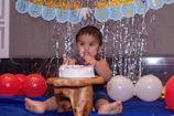 girl in pink tank top sitting on blue inflatable pool with cake on top