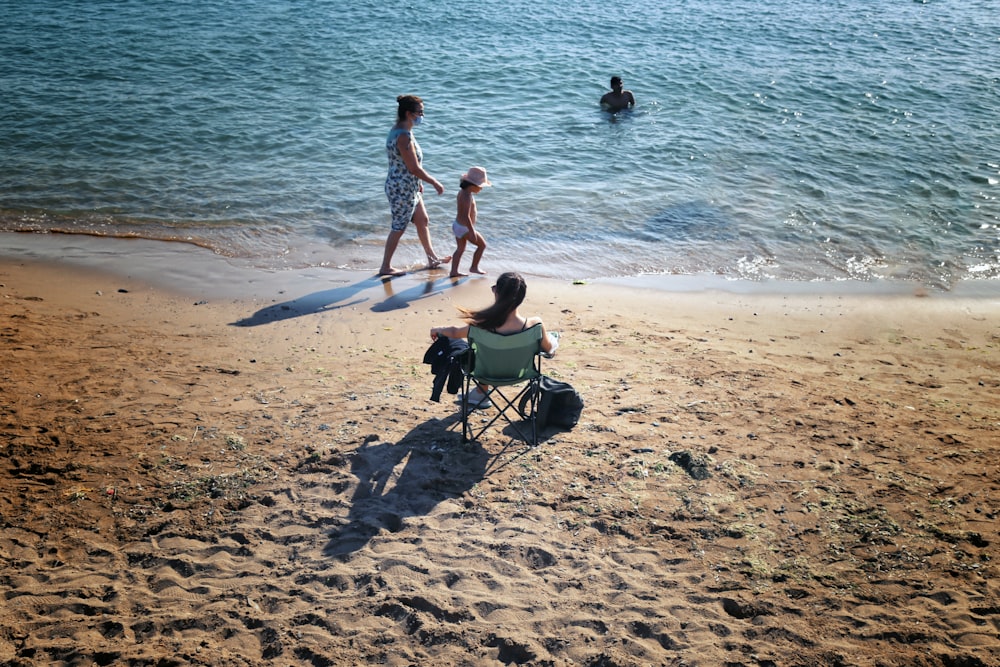 2 women sitting on green camping chair on beach during daytime