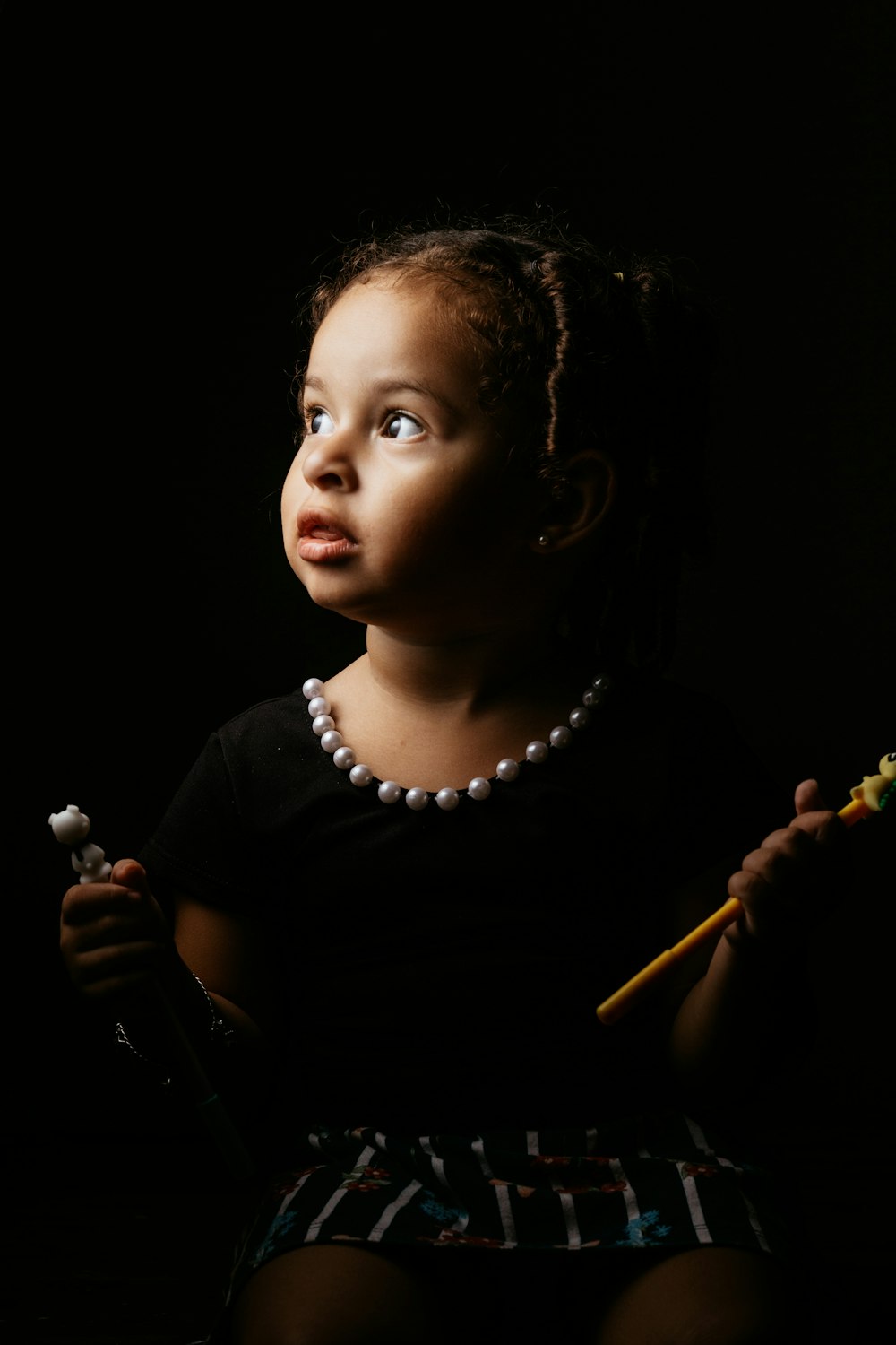 girl in black shirt holding brown stick