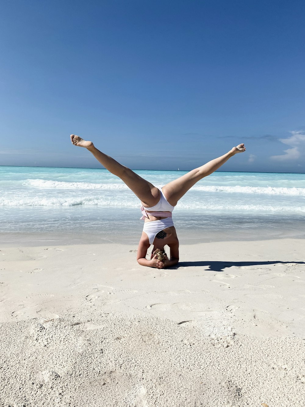 woman in white tank top and white shorts jumping on beach during daytime