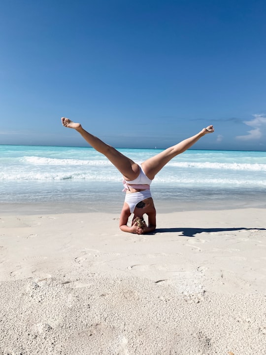 woman in white tank top and white shorts jumping on beach during daytime in Spiagge Bianche Rosignano Italy