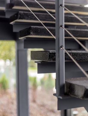 Modern industrial railing installed on a stylish outdoor staircase with charcoal background.