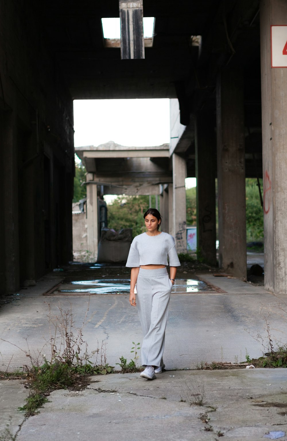 woman in white long sleeve shirt and gray pants standing on gray concrete floor