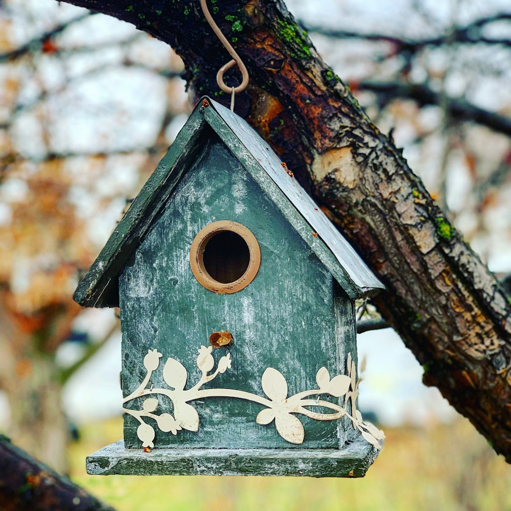 昼間の木の枝の上の茶色の木製の鳥の家