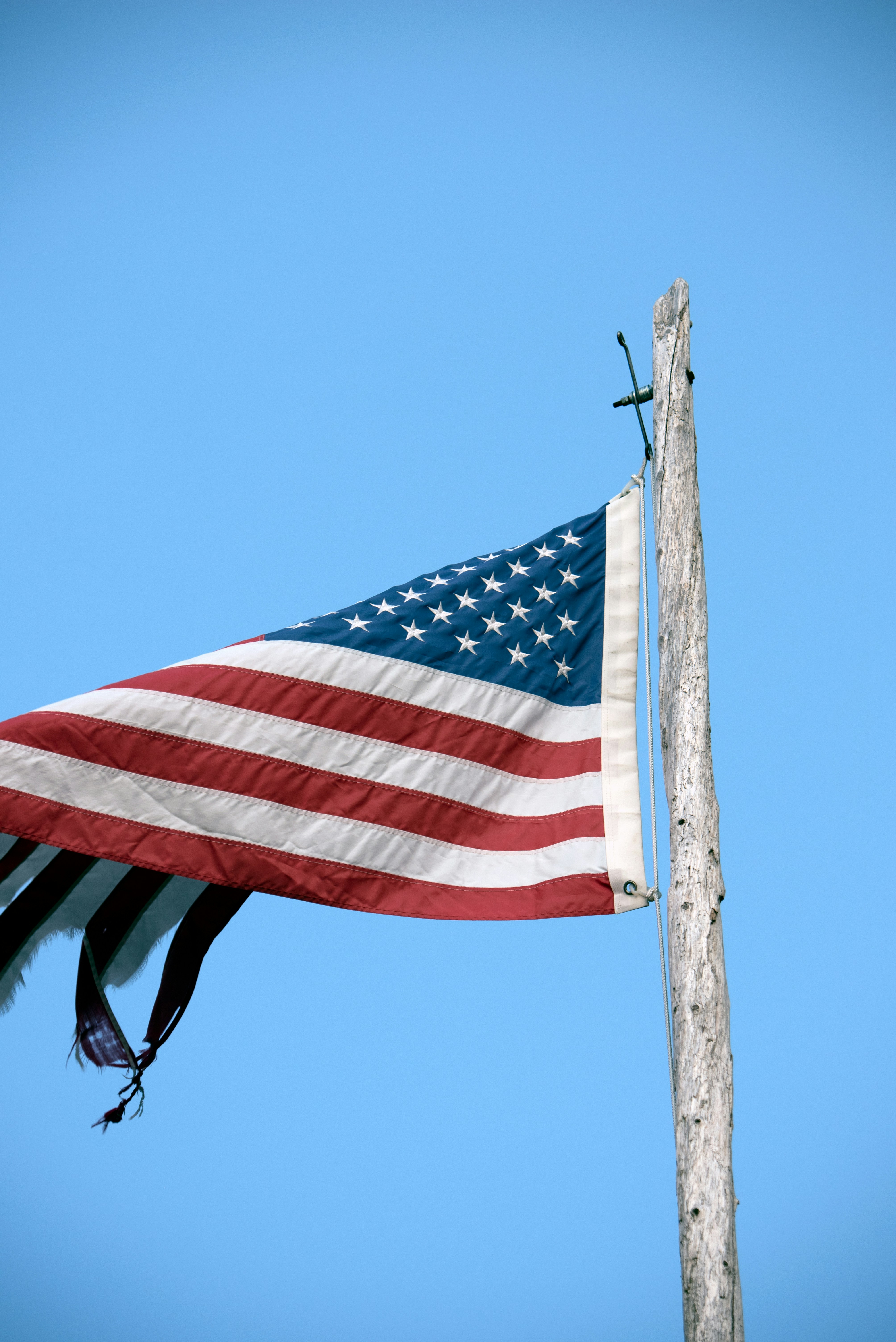 us a flag on brown wooden pole during daytime