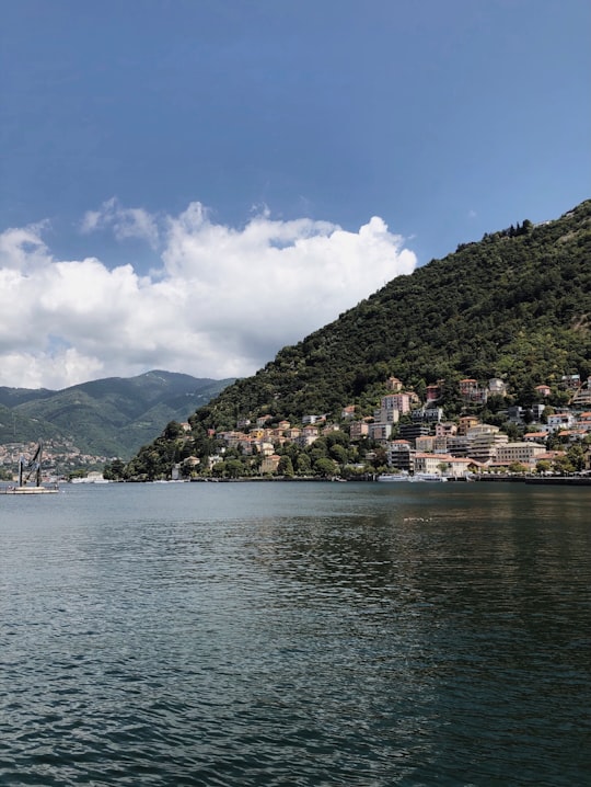 green mountain beside body of water under blue sky during daytime in Lake Como Italy