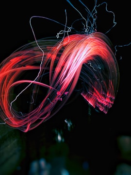 Futuristic film reel spinning with neon light trails in dark purple and red.