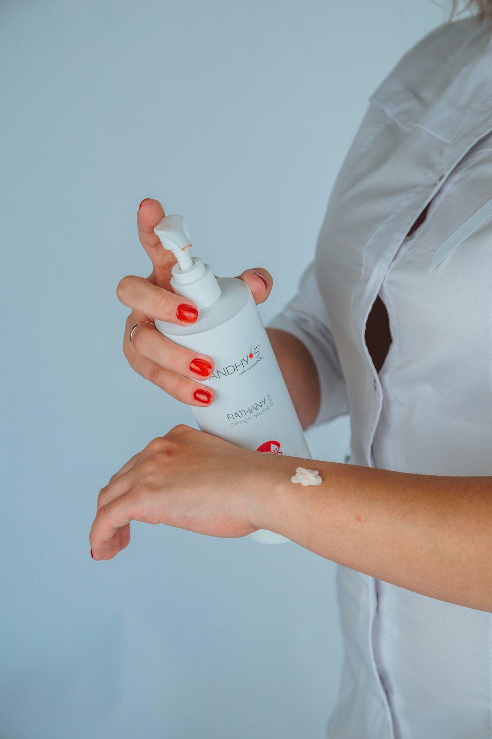 woman in white button up shirt holding white plastic bottle