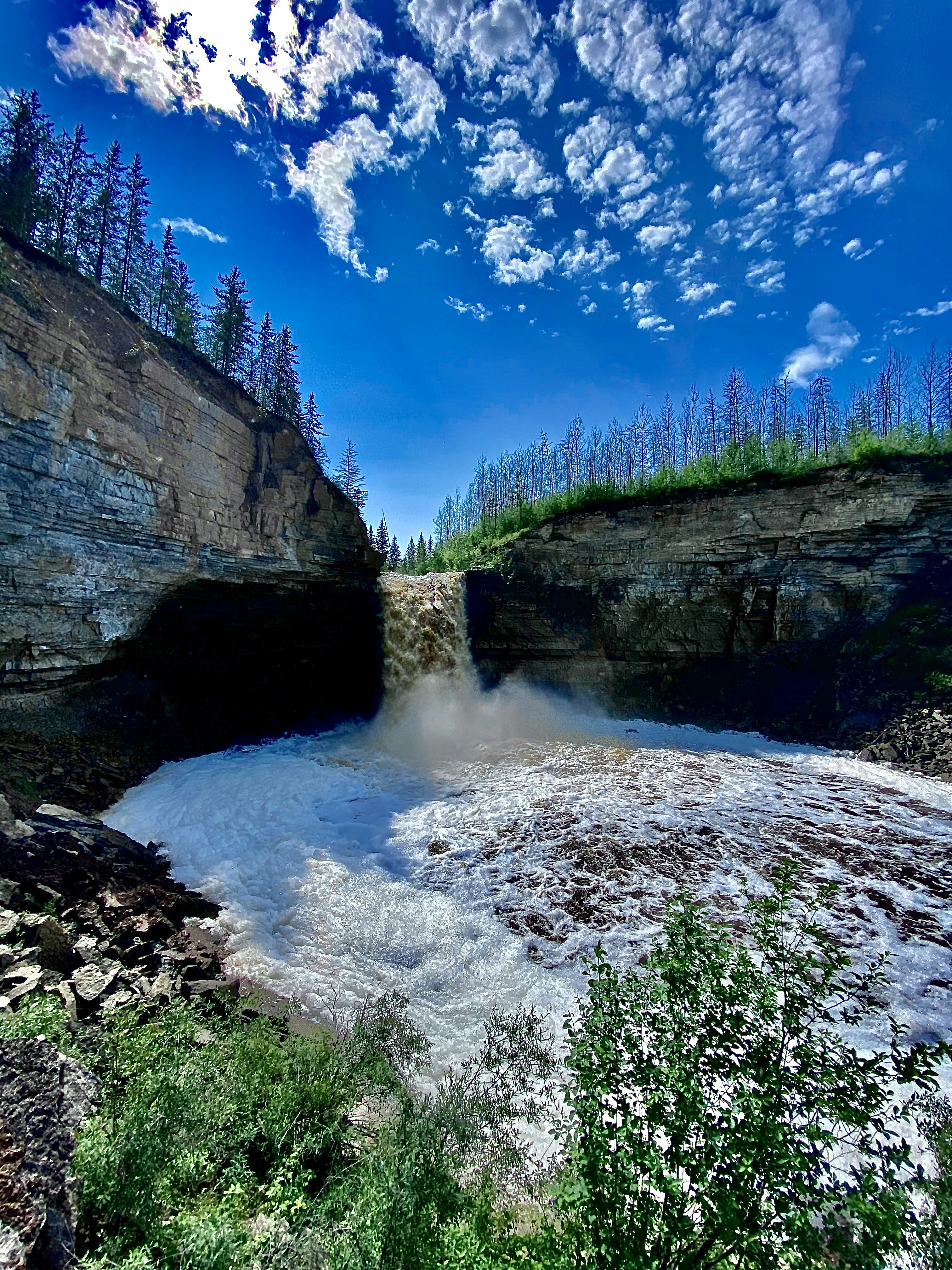 green and brown rocky mountain beside river under blue sky during daytime
