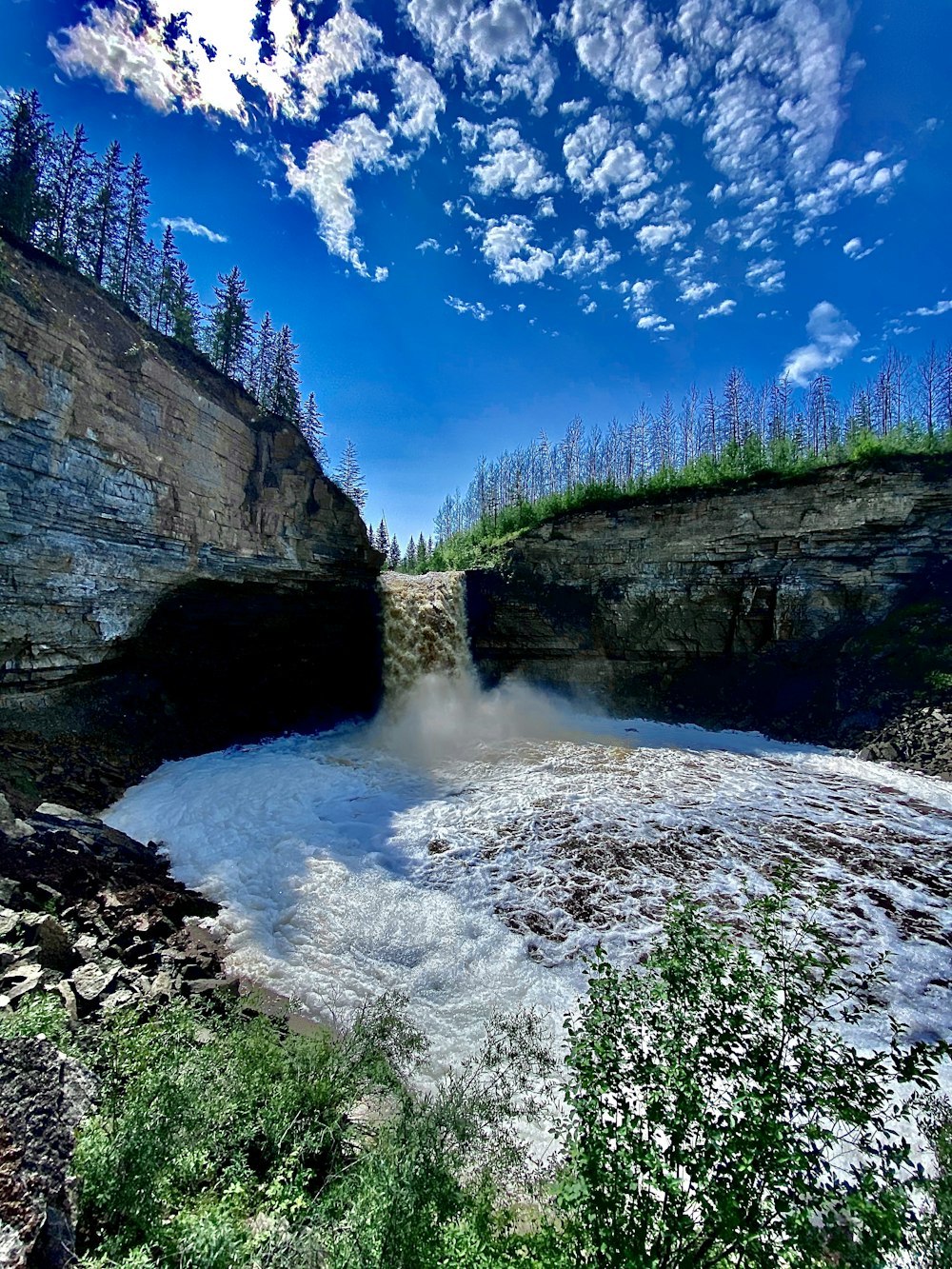 green and brown rocky mountain beside river under blue sky during daytime