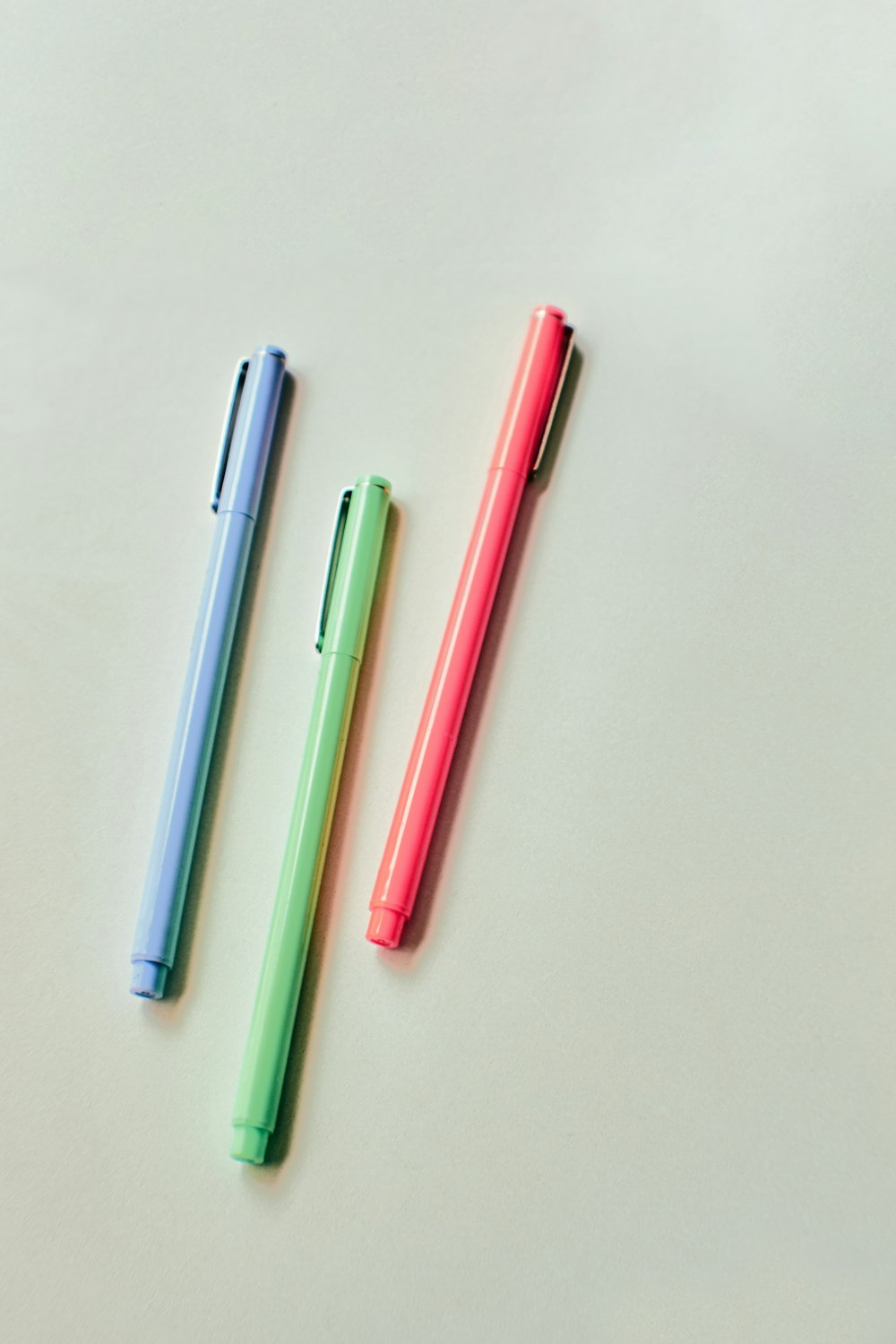 bolígrafo rosa y azul sobre mesa blanca