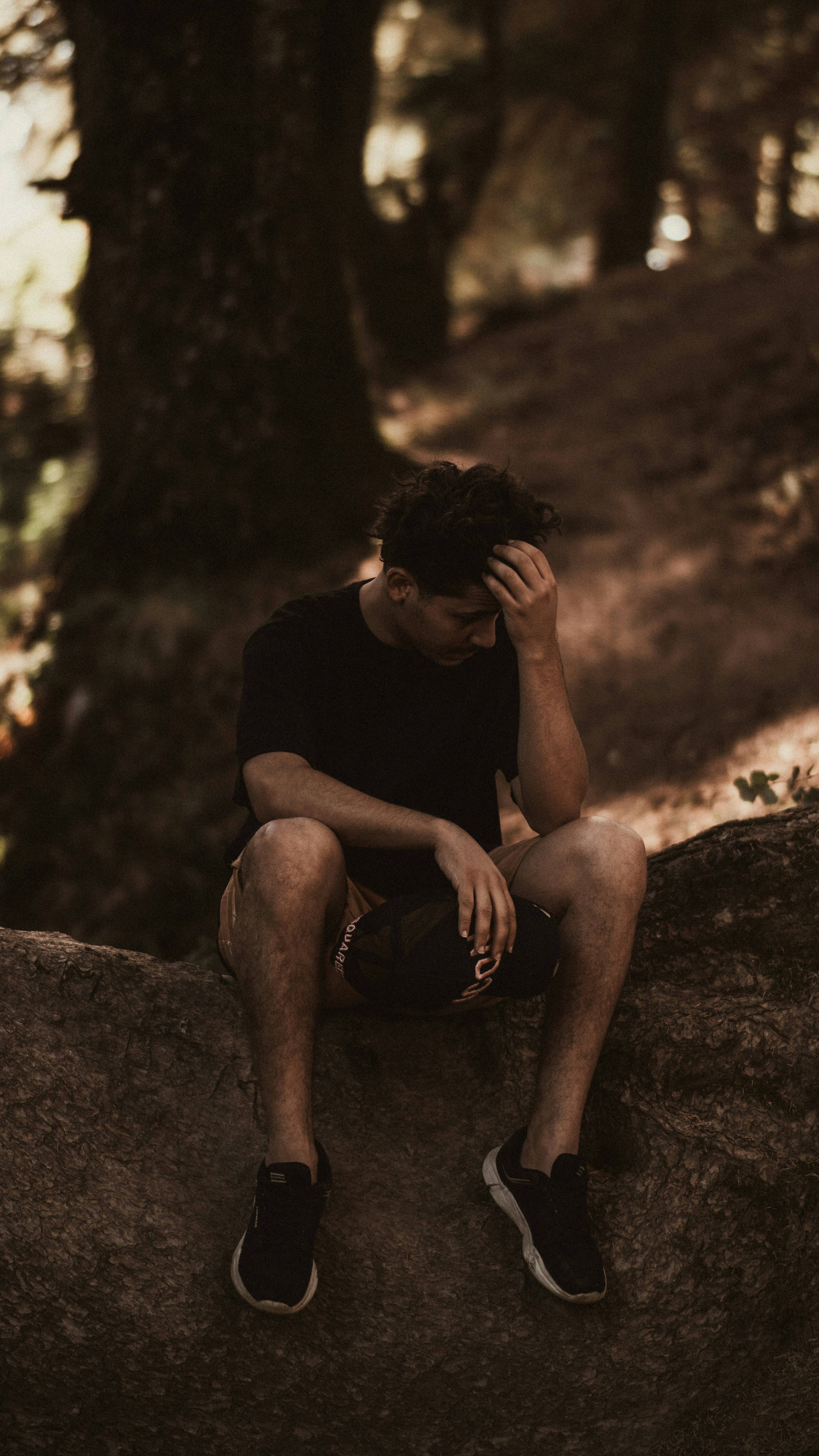 man in black crew neck t-shirt sitting on rock
