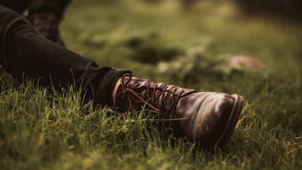 person in brown leather boots lying on green grass during daytime
