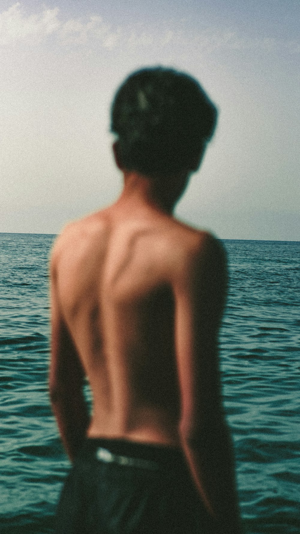 topless woman standing on sea during daytime