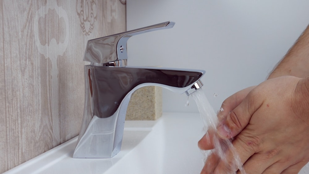 person holding stainless steel faucet