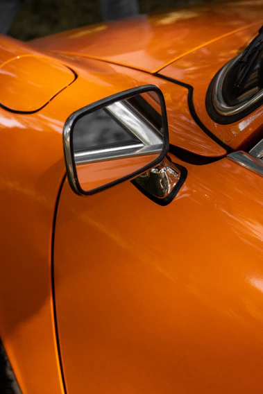 A close-up of a shiny, freshly repaired car door reflecting the sunlight.