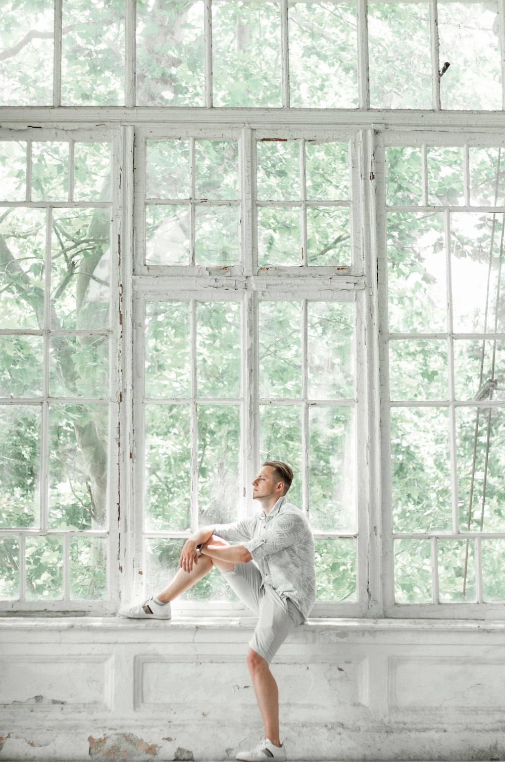 uomo in camicia bianca in piedi accanto alla finestra durante il giorno
