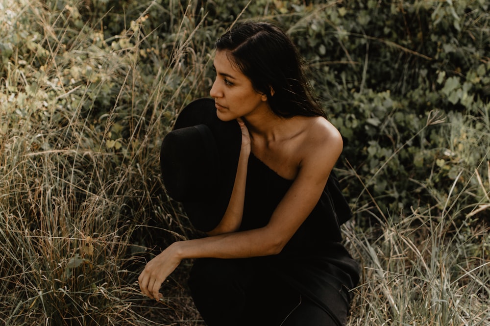 woman in black tank top sitting on brown grass during daytime