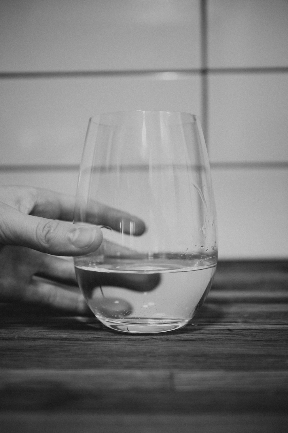 grayscale photo of person holding drinking glass