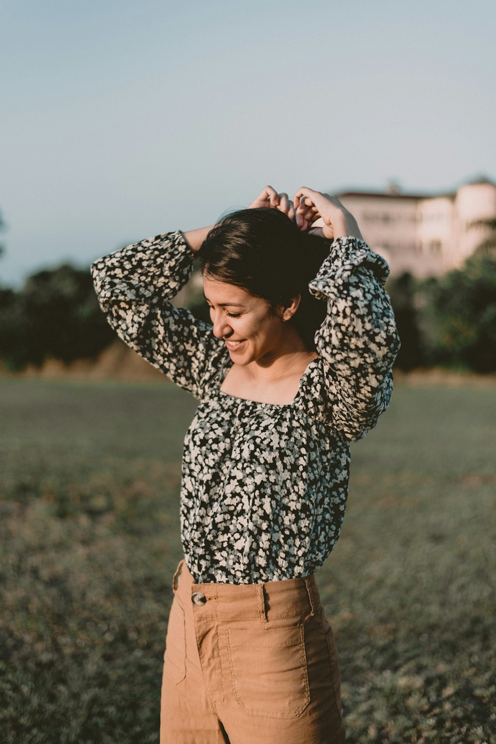 woman in black and white floral long sleeve shirt and brown denim shorts standing on field