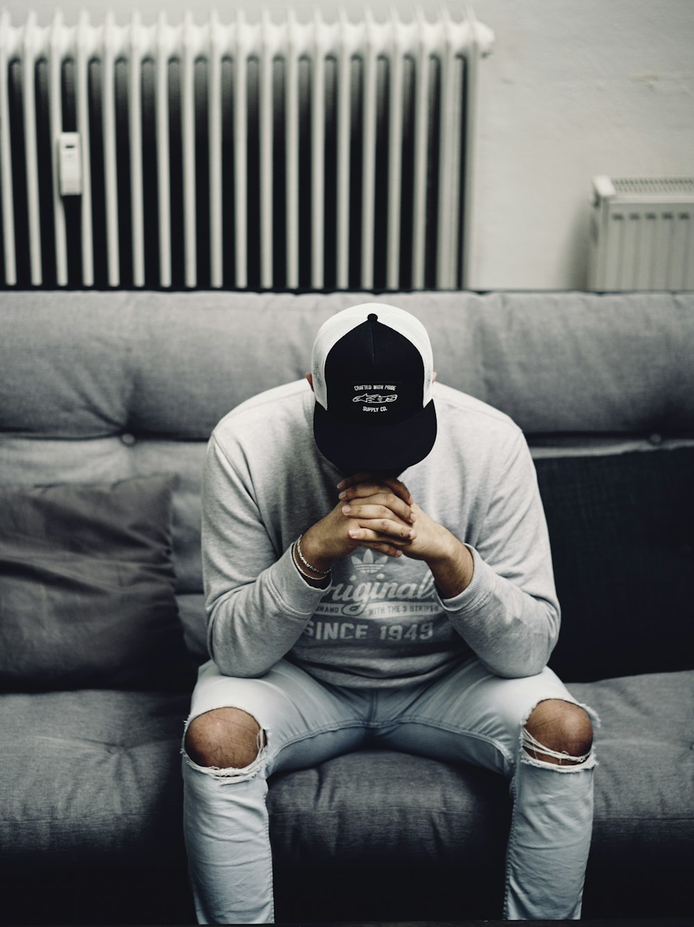 man in white long sleeve shirt and blue denim jeans sitting on black couch